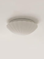 Shown from the side, this Clérachic ceiling light's white ribbed shade sits unlit on a plain white backdrop.