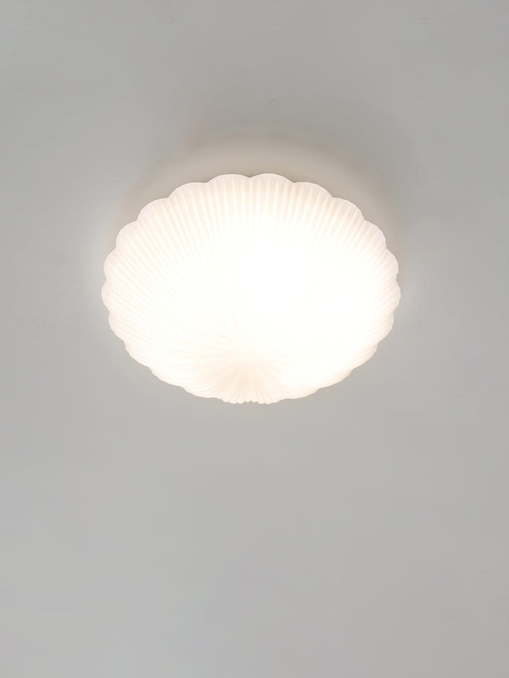Front-on and lit, this Clérachic ceiling light glows warm white in a pale, softly lit room.