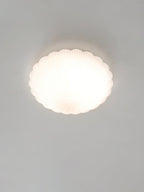 Front-on and lit, this Clérachic ceiling light glows warm white in a pale, softly lit room.