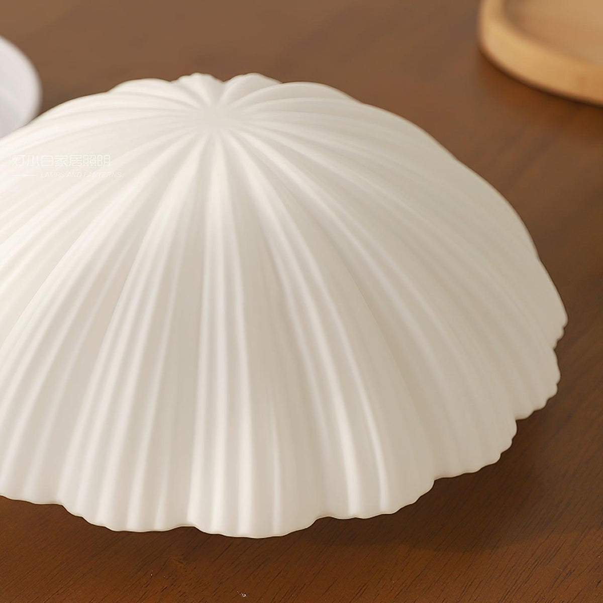 Close view of the pleated ribs on this Clérachic ceiling light, shown unlit on a wood tabletop.