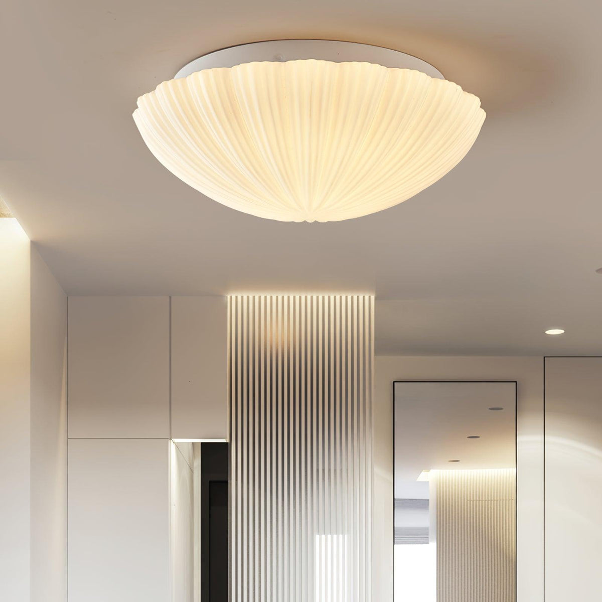 A ribbed, shell-shaped ceiling light glows warm white above a mirrored hallway wall, from Clérachic.