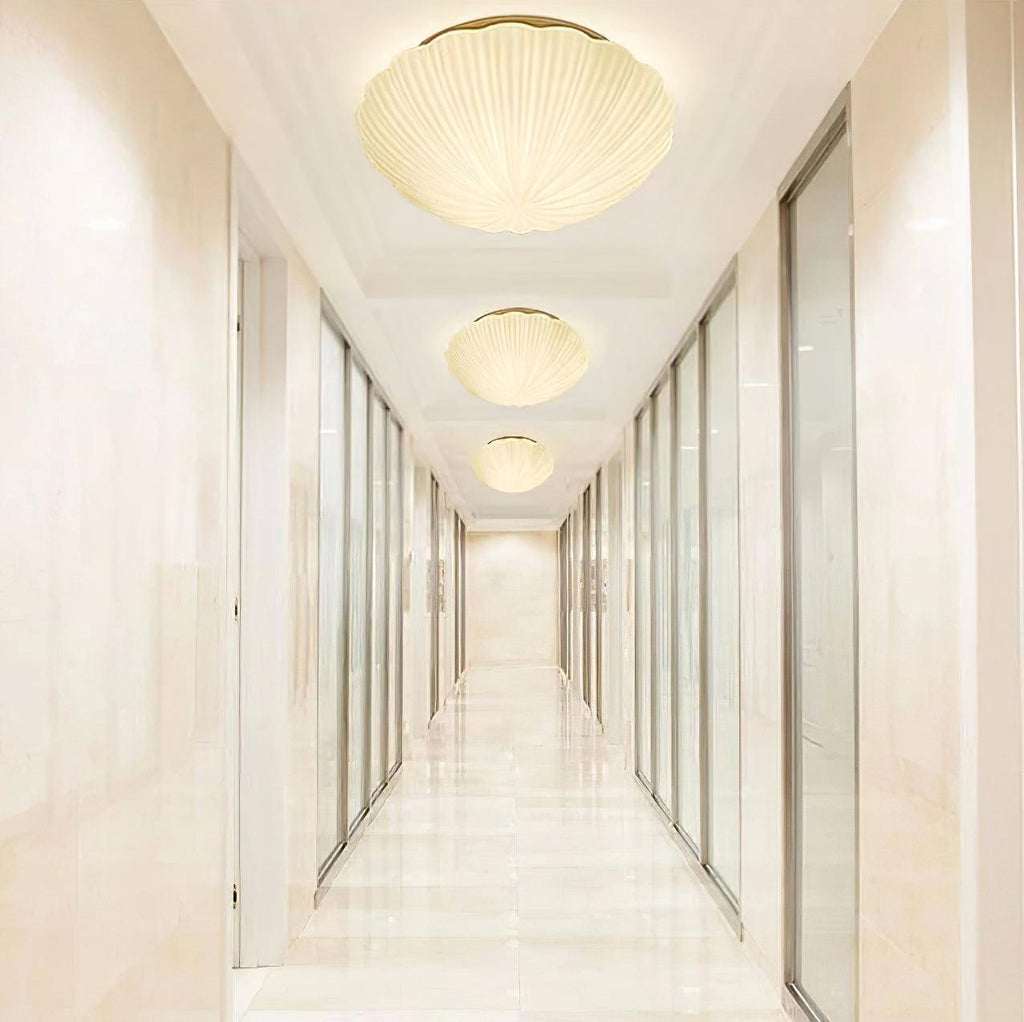 Three of this Clérachic ceiling light hang in a row along a marble-floored hallway, each glowing warm white.
