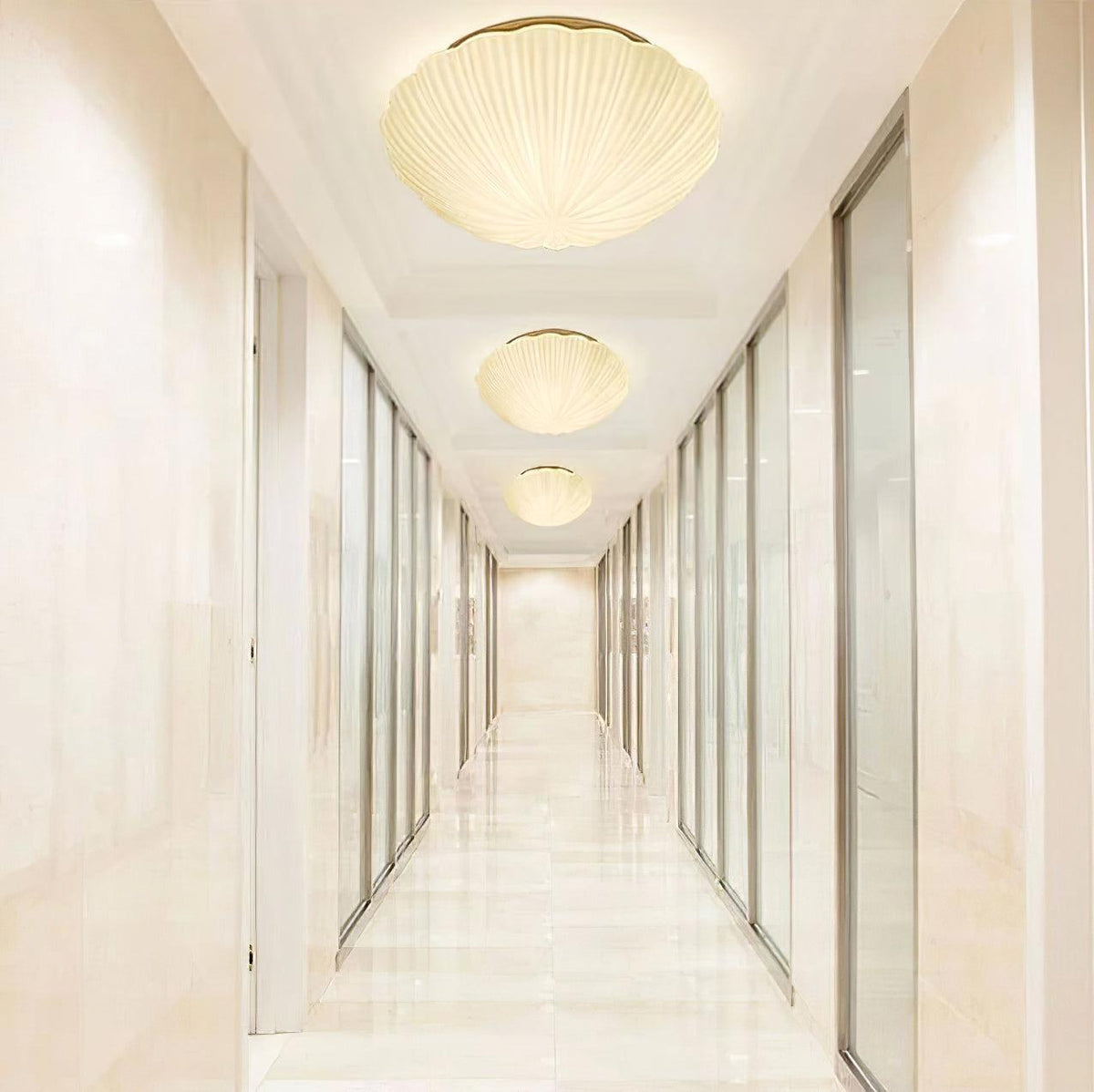 Three of this Clérachic ceiling light hang in a row along a marble-floored hallway, each glowing warm white.