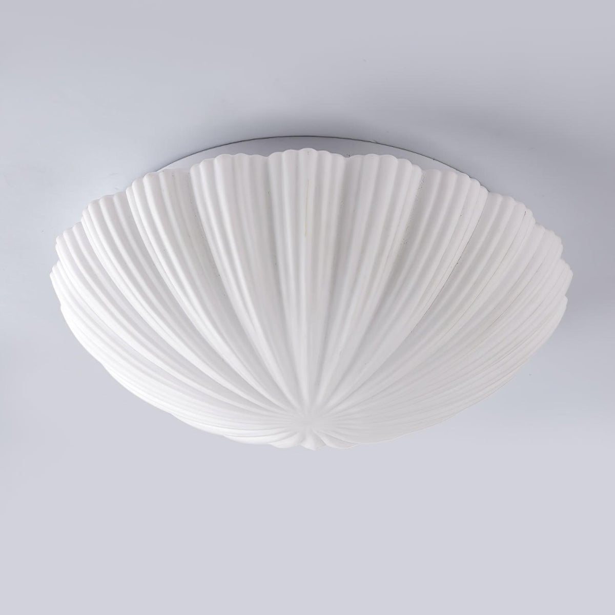 Unlit on a plain grey backdrop, this Clérachic ceiling light shows the scalloped edge of its shade in side view.