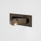 Bronze LED bedside reading light shown flush against the wall