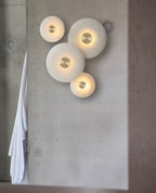 Tall view of the four-disc alabaster arrangement lit on a concrete pillar, towel hanging to the left.