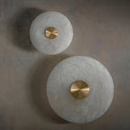 Two alabaster disc wall lights switched off, showing the raw stone grain and polished brass caps.