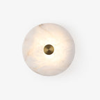Alabaster disc wall light on a plain white background, lit to reveal its amber stone veining.