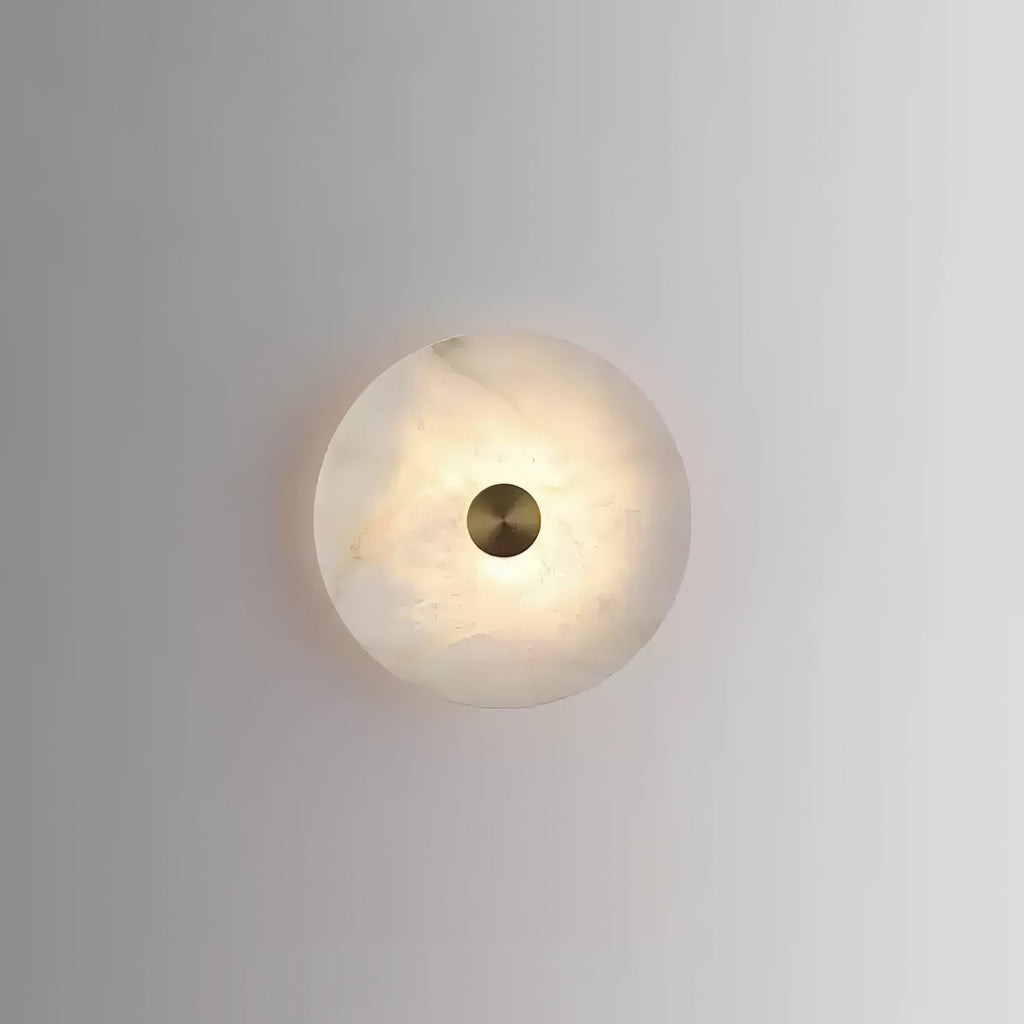 Alabaster disc wall light seen straight on, its warm veining showing through around the brass cap.