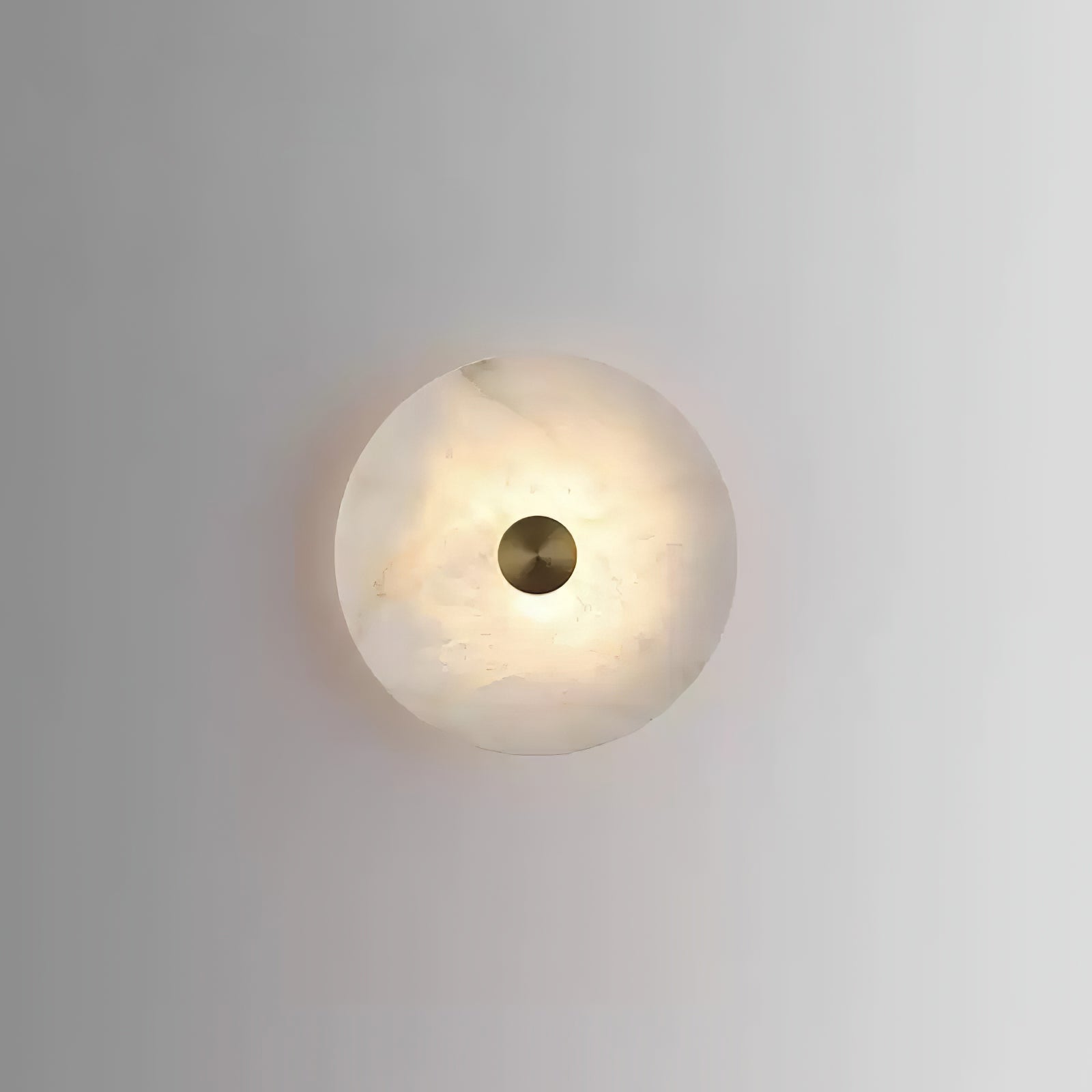Alabaster disc wall light seen straight on, its warm veining showing through around the brass cap.