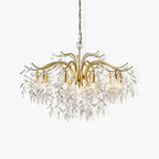The chandelier on white, hung from a brass chain with crystal leaves clustered under each lamp.