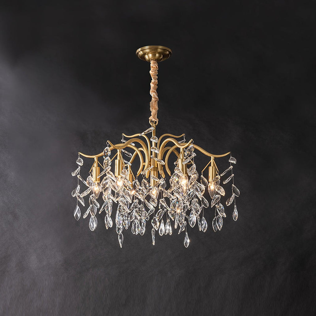 Brass chandelier on dark grey, clear crystal leaves hanging from curved arms below the ceiling plate.