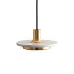 Close angled view of a white marble disc pendant trimmed in gold, its short brass neck catching the light against a white backdrop, by Clérachic.