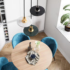 Overhead view of three Clérachic pendant lights in mixed finishes above a round table ringed by blue velvet chairs.