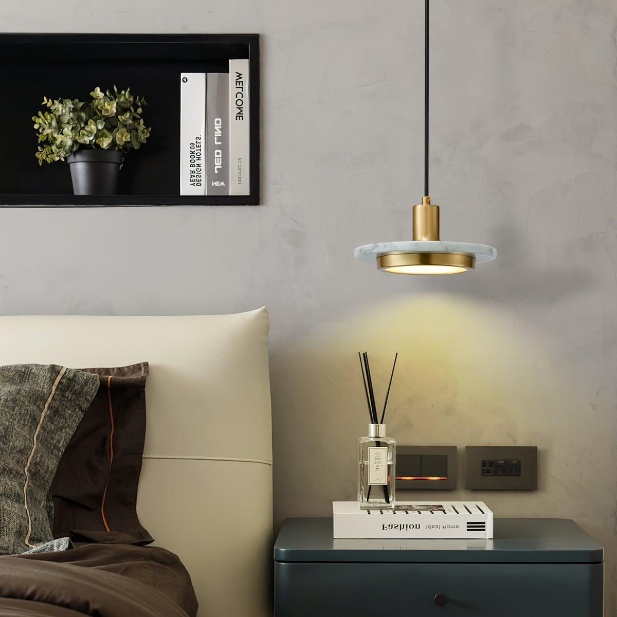 A Clérachic pendant light glows warm beside a cream armchair, lighting a reed diffuser on the side table.