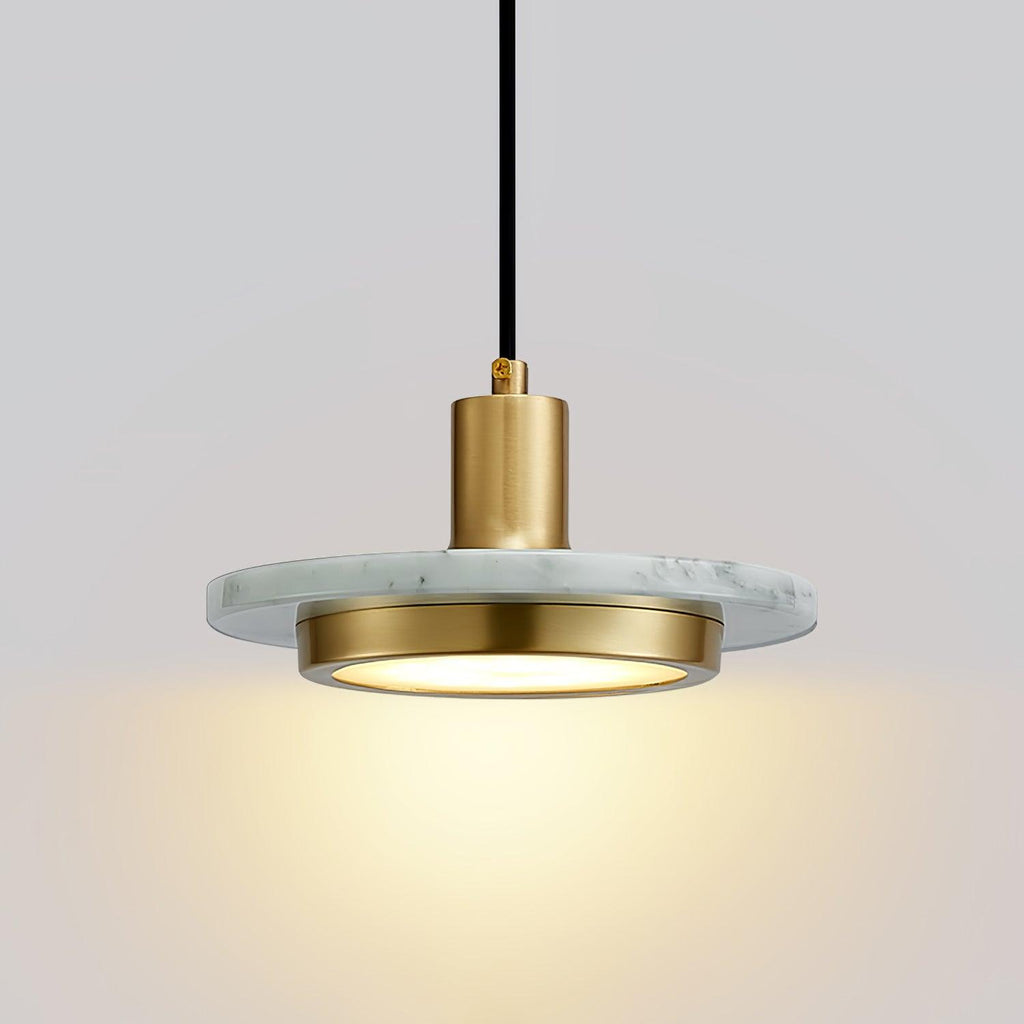 Close-up of a white marble Clérachic pendant light, its gold cylinder socket catching the light above the disc.