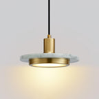 Close-up of a white marble Clérachic pendant light, its gold cylinder socket catching the light above the disc.