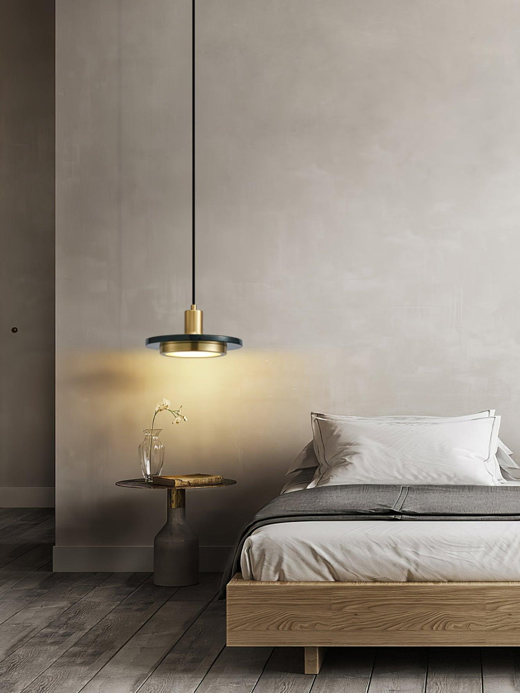The same bedside Clérachic pendant cropped tighter, its warm glow spreading further up the grey wall behind it.