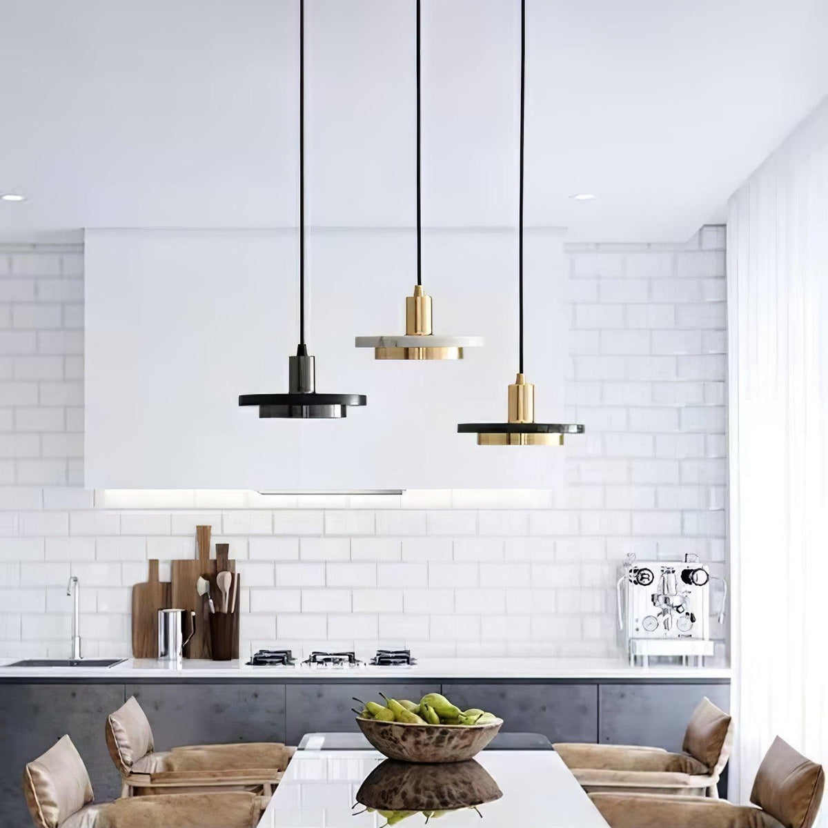 Three Clérachic pendant lights at different heights hang above a white-tiled kitchen island with fruit.