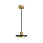 The same dark stone disc pendant hangs against a clean white backdrop, its full brass-topped cord visible in this Clérachic studio shot.