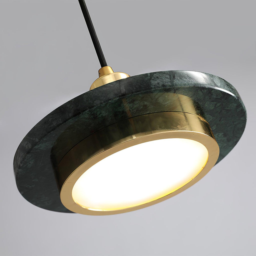 Angled close-up of a green marble Clérachic pendant light's underside, its LED glowing through the gold ring.