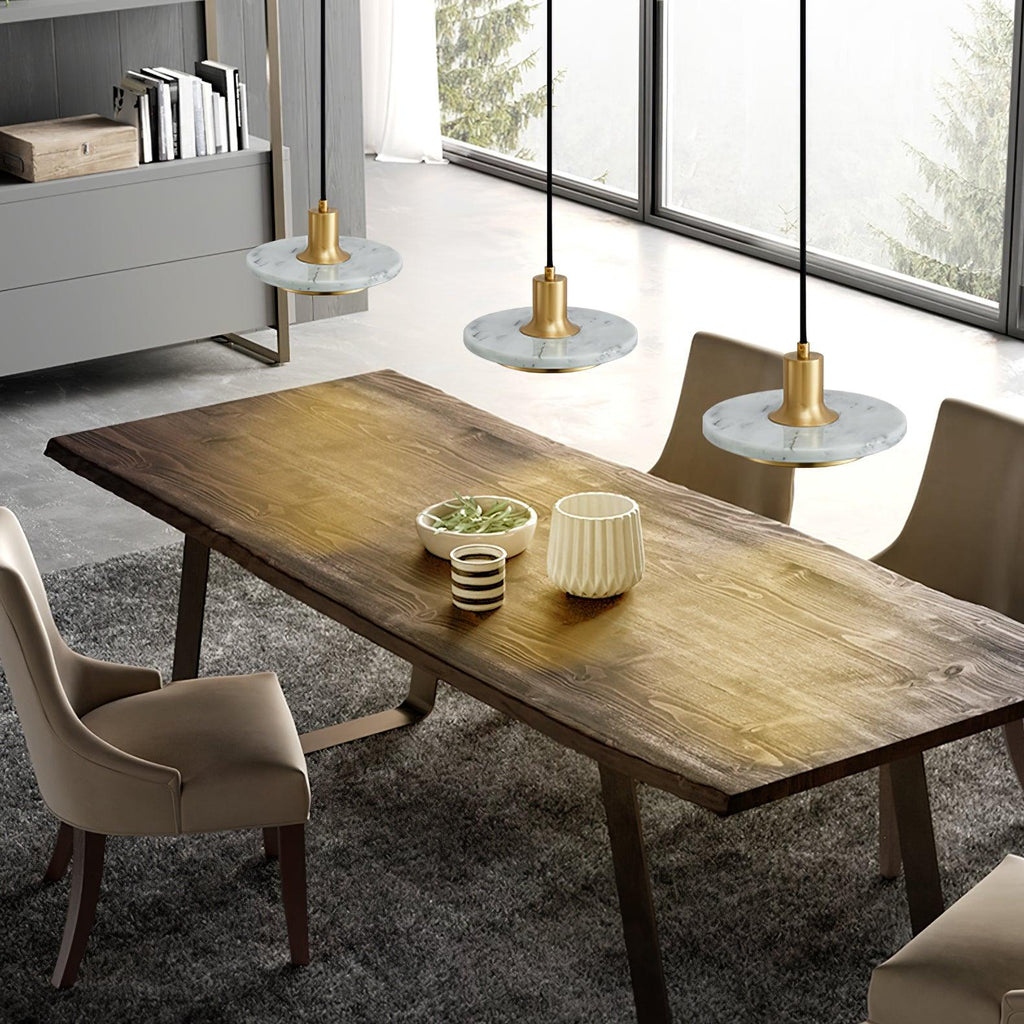 Three white marble Clérachic pendant lights hang above a rustic wood table beside tall industrial windows.