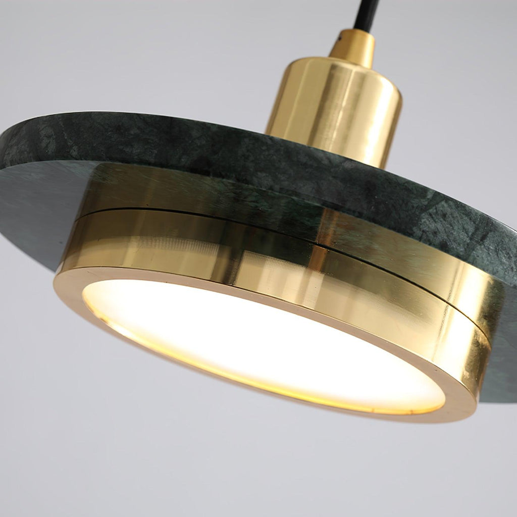 Angled close-up of a green marble Clérachic pendant light's gold rim and glowing disc seen from below.