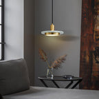 A Clérachic pendant light glows warm beside a grey sofa, lighting dried pampas grass on a small side table.