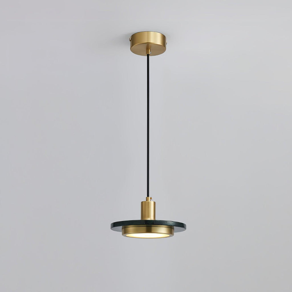 Clérachic pendant with a dark stone disc glowing softly beneath its brass fitting, framed closer on its cord against pale grey.
