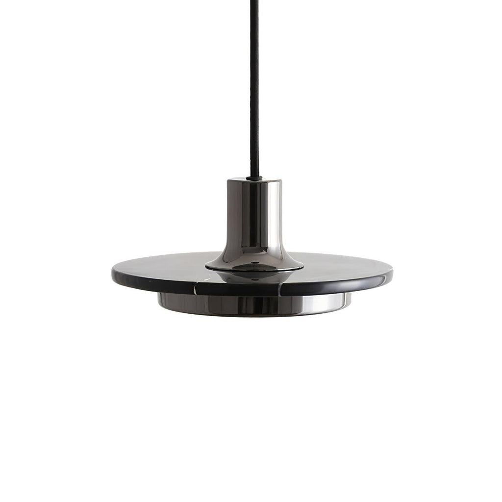 Underside close-up of a dark gunmetal disc pendant, angled to show its brass neck meeting the shade, shot on white for Clérachic.