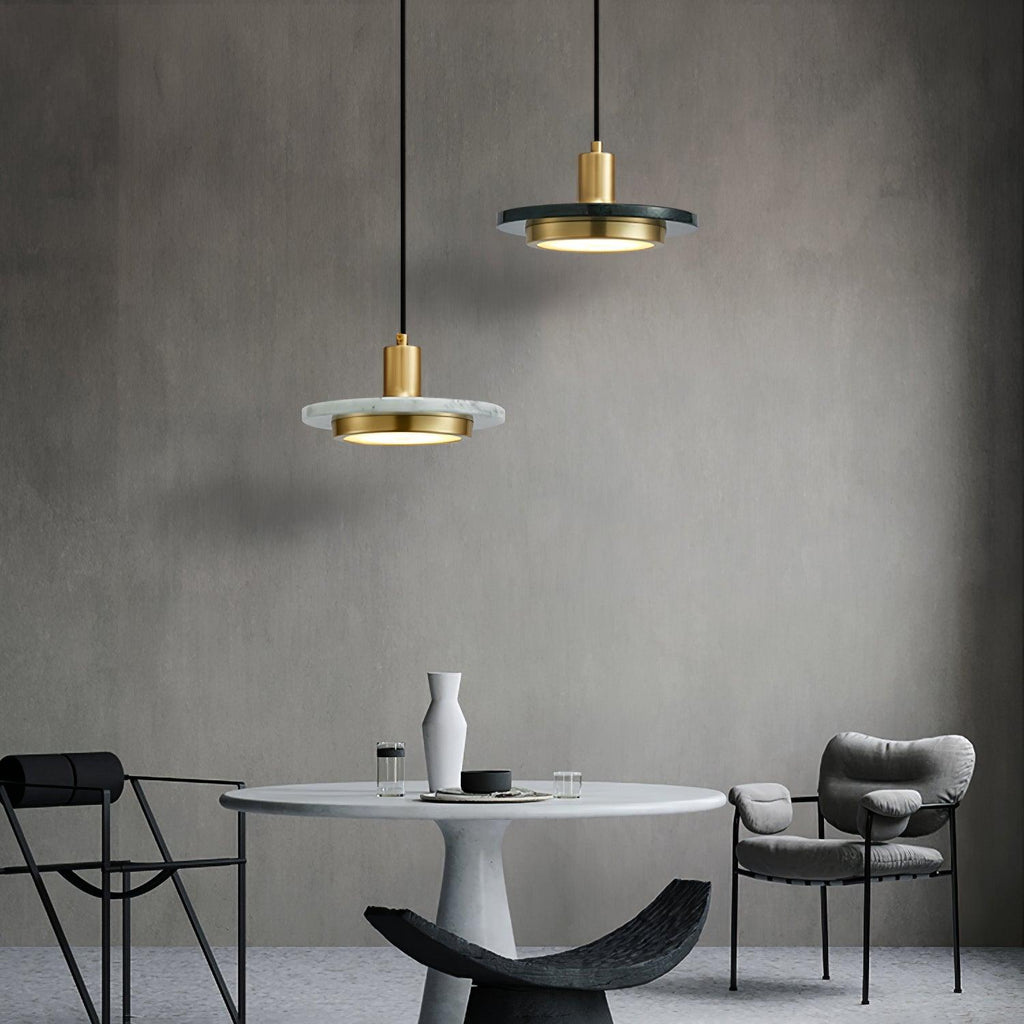 Two Clérachic pendant lights glow at different heights above a round marble table with grey chairs.