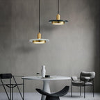 Two Clérachic pendant lights glow at different heights above a round marble table with grey chairs.