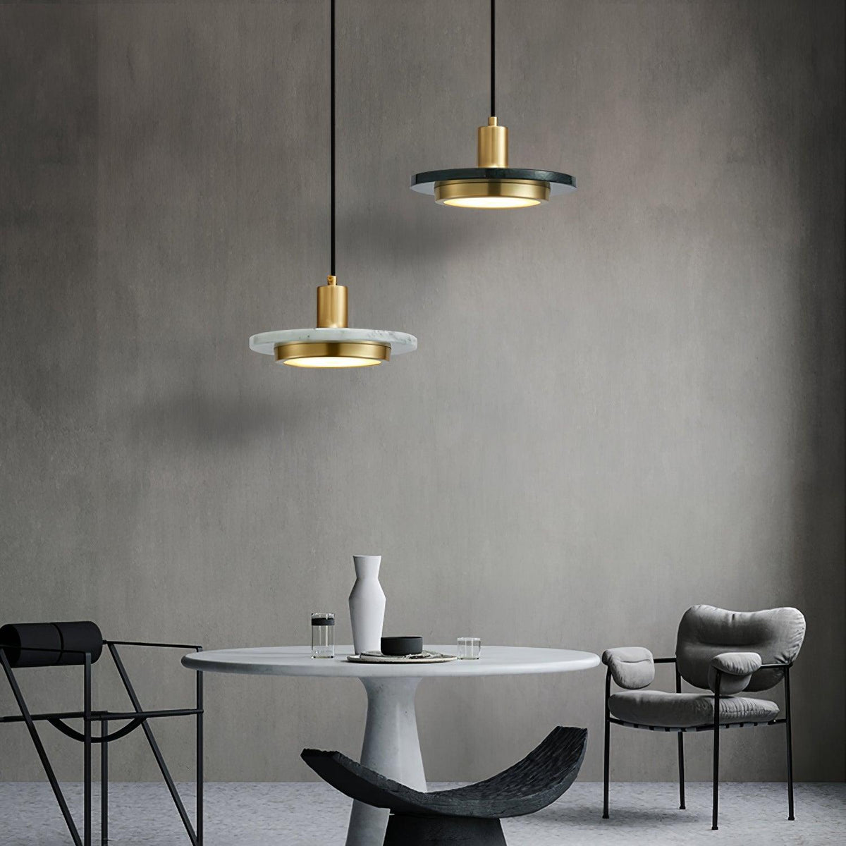 Two Clérachic pendant lights glow at different heights above a round marble table with grey chairs.