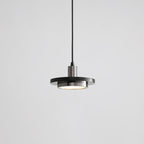 A matt dark disc pendant with a brushed steel-toned fitting drops on its black cord in this grey-background shot from Clérachic.