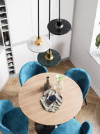 Three Clérachic pendant lights in white, black and green marble hang above a round table with blue chairs.