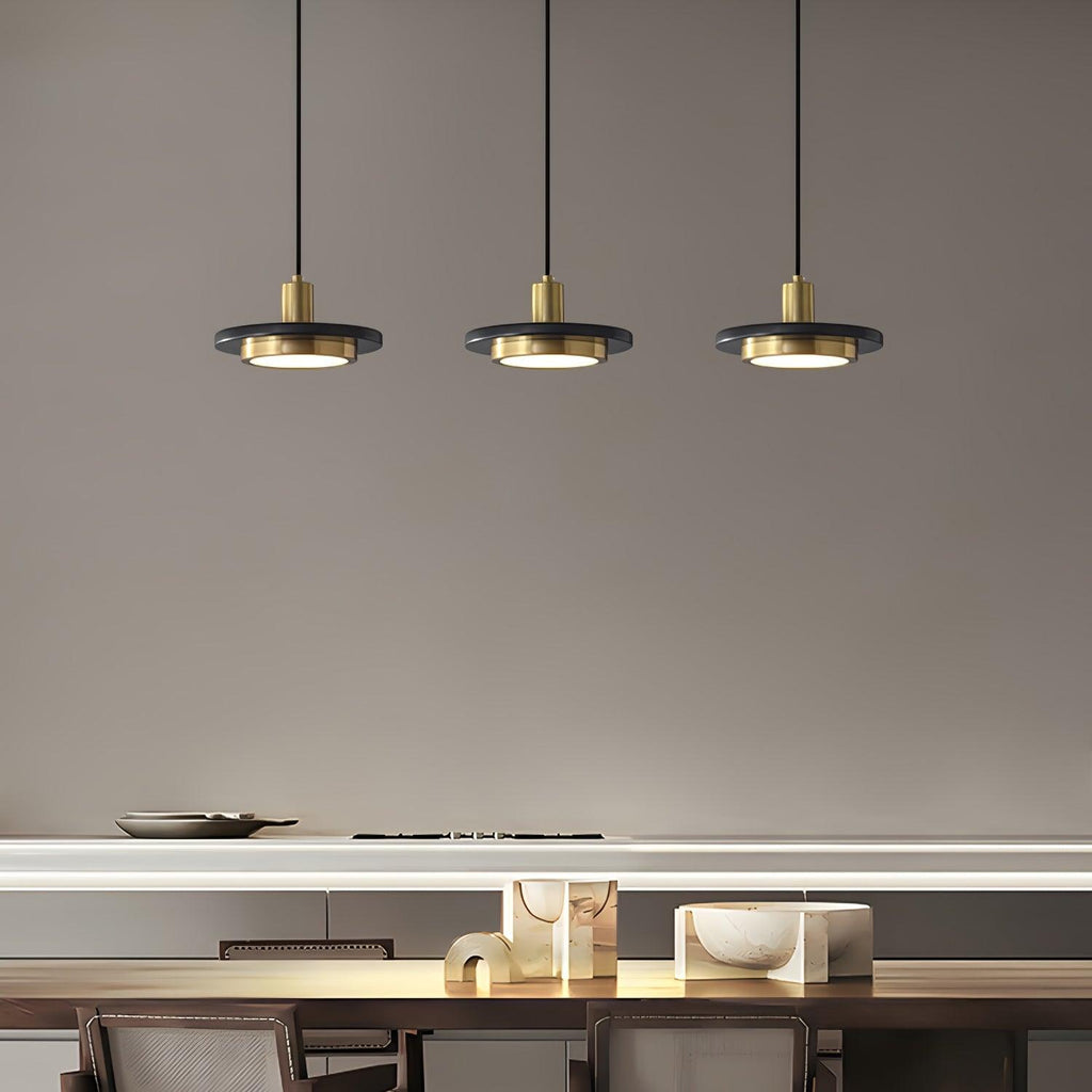 Three Clérachic pendant lights hang above a table laid with plates and gold-accented décor in a dining nook.
