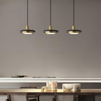 Three Clérachic pendant lights hang above a table laid with plates and gold-accented décor in a dining nook.