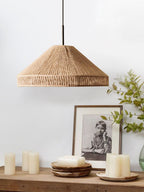A console styled with pillar candles and a framed black-and-white portrait sits beneath this Clérachic pendant.