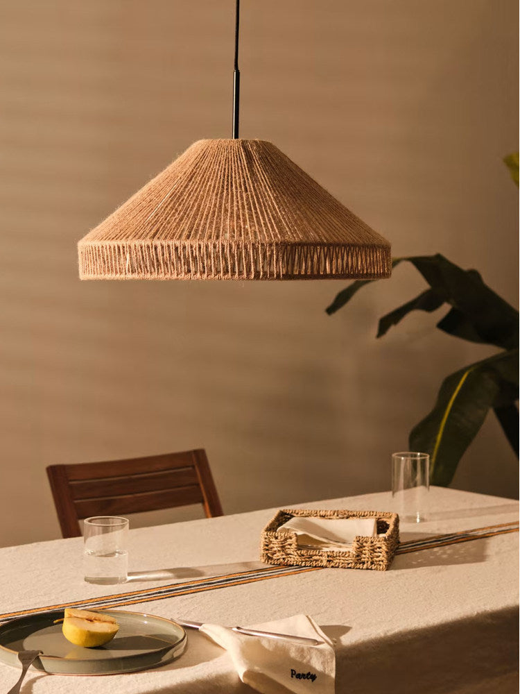 This Clérachic pendant lights a linen-set table holding a woven tray, glassware and a plate with a lemon half.