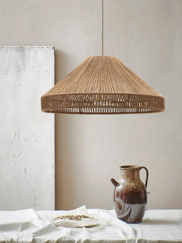This Clérachic pendant hangs against a textured plaster wall above a small ceramic jug and a plate of grains.
