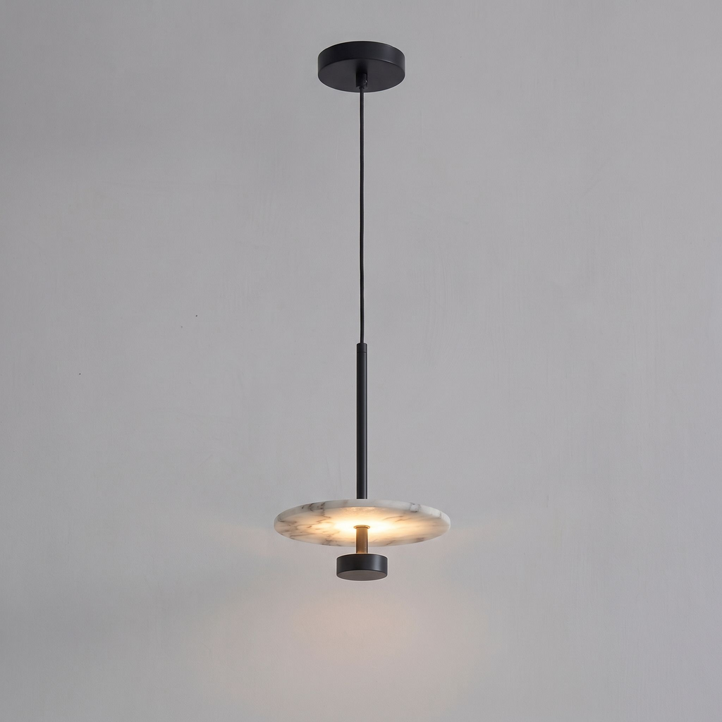 Shown lit against grey, this black Clérachic pendant drops its glowing alabaster disc from a slender rod.