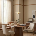 Over a round breakfast table with beige chairs, this brass Clérachic pendant glows in a sunlit nook.
