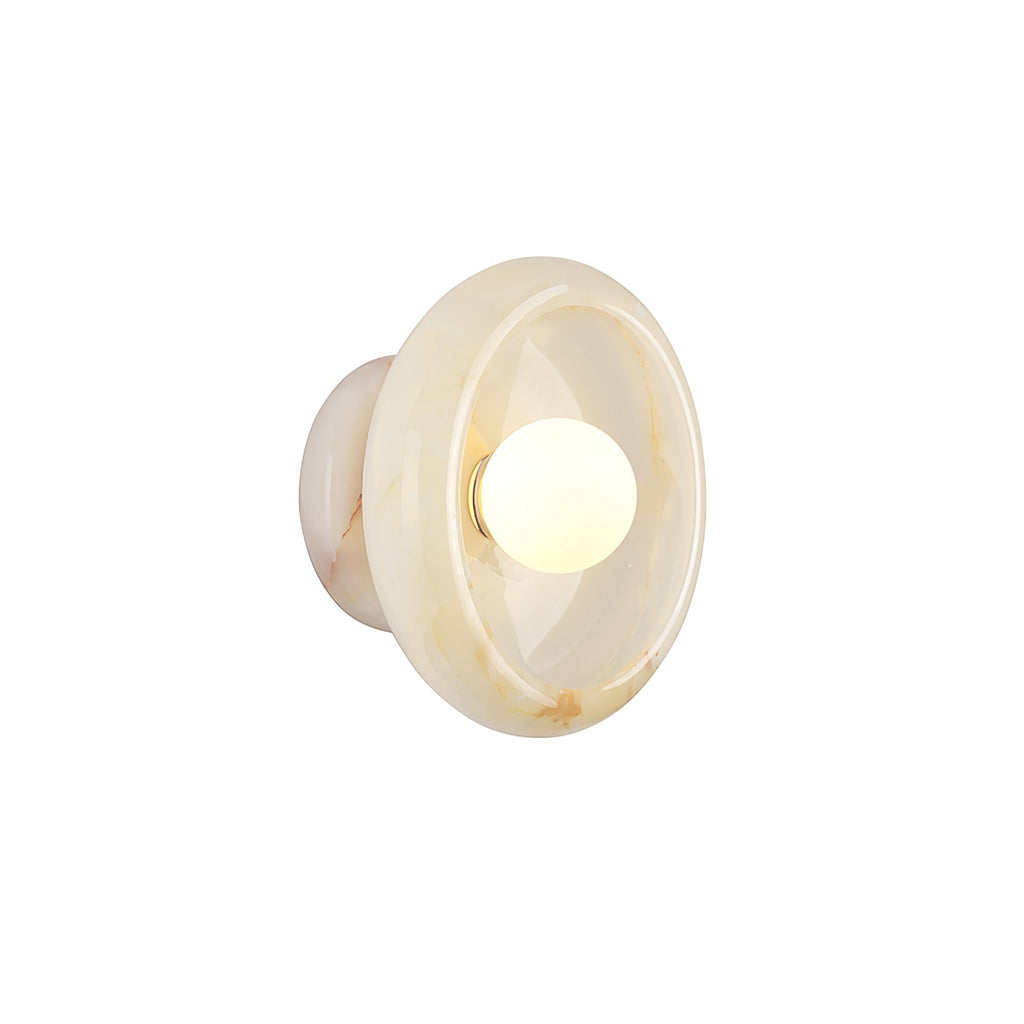 Clérachic cream jade wall sconce lit on a white studio background, the bulb glowing at the centre of the disc.