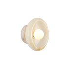 Clérachic cream jade wall sconce lit on a white studio background, the bulb glowing at the centre of the disc.