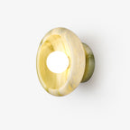 Clérachic wall sconce in green-yellow jade lit on a white studio background, its marbled pattern visible.