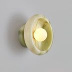 Clérachic wall sconce in swirled green jade, its marbled pattern lit from the glowing bulb at centre.