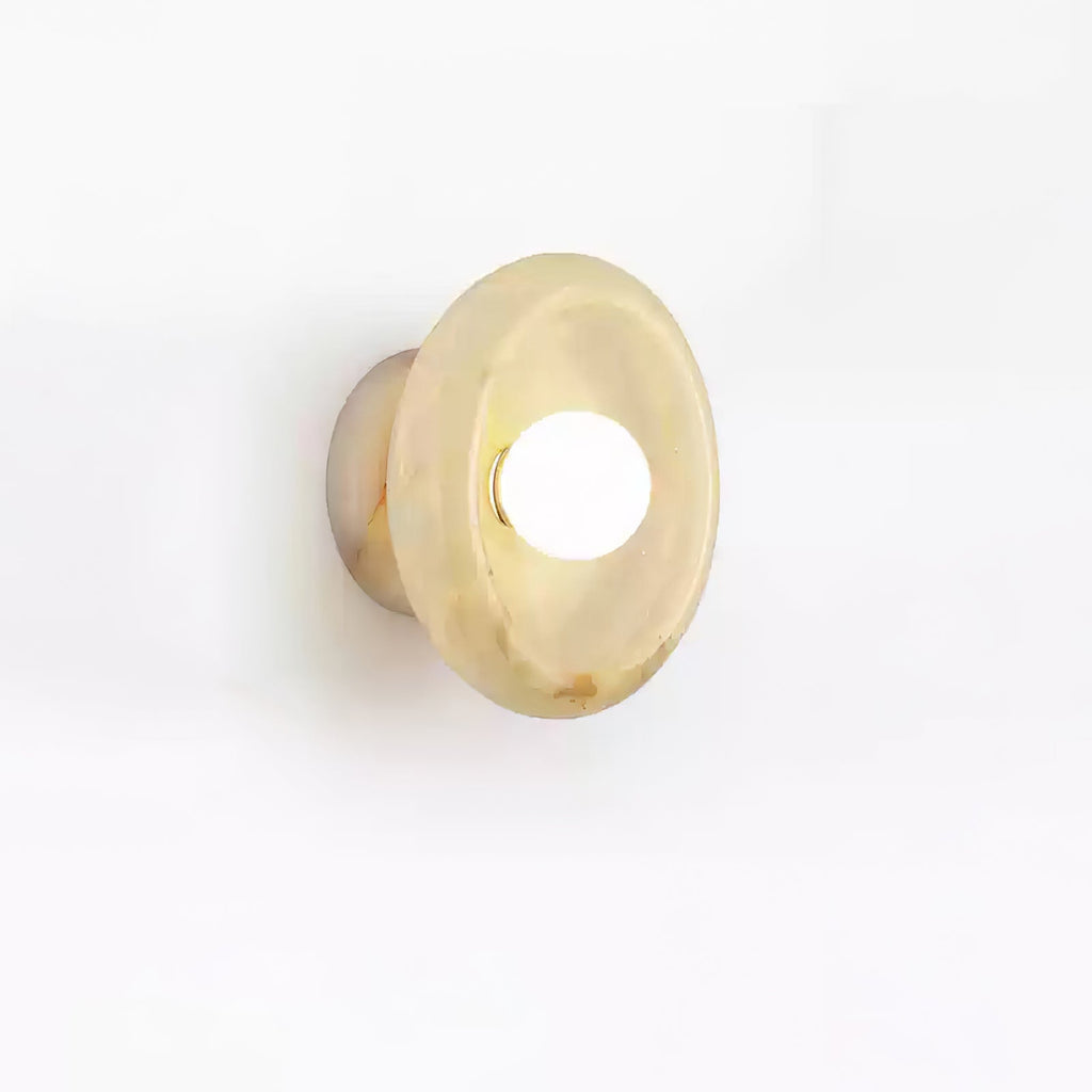 Clérachic beige jade wall sconce photographed at an angle on white, its warm marbled tones catching the light.