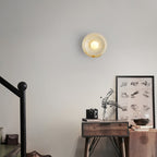 Clérachic jade wall sconce lit above a wooden side table holding a camera and a framed sketch near a staircase.