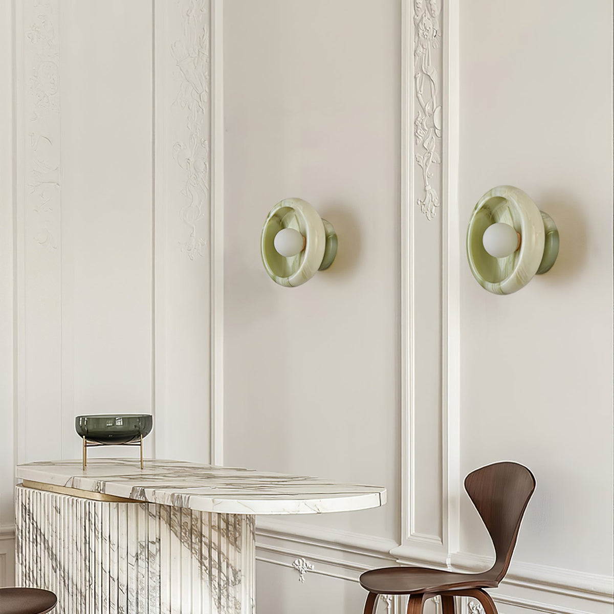 Two Clérachic green jade wall sconces mounted either side of a small marble-topped dining nook.