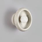 Clérachic wall sconce in veined white marble, its grey striations visible around the glowing central bulb.